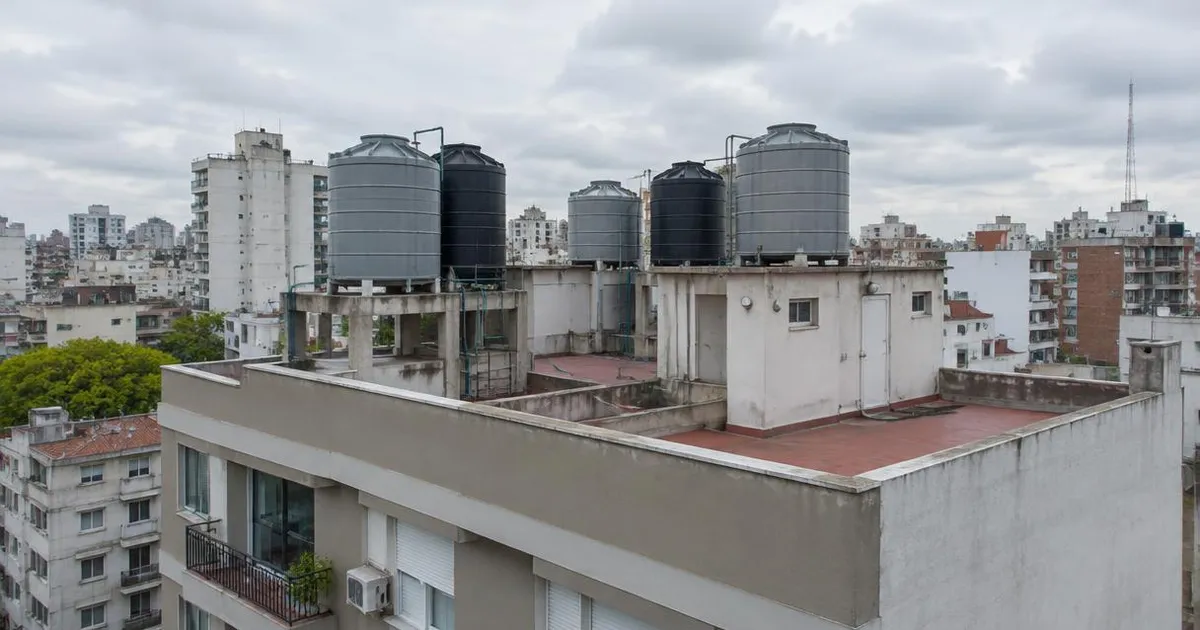 Varios tanques de agua sobre la azotea de un edificio de departamentos en un día nublado